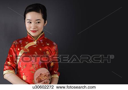Young woman in cheongsam holding a fan on her left side View Large Photo Image Stock Image - Young woman in cheongsam holding a fan on her left side. Fotosearch