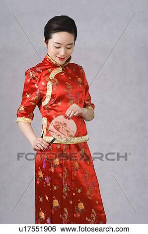 Stock Photograph - Young woman in cheongsam holding a fan. Fotosearch