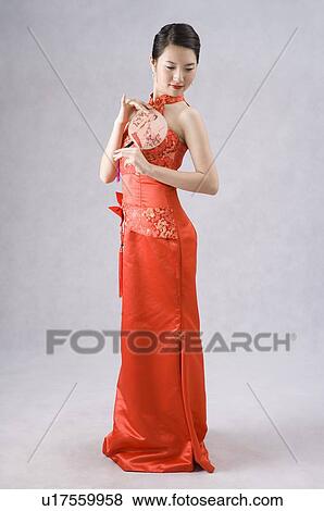 Young woman in cheongsam holding a folding fan View Large Photo Image Stock Photo - Young woman in cheongsam holding a folding fan. Fotosearch