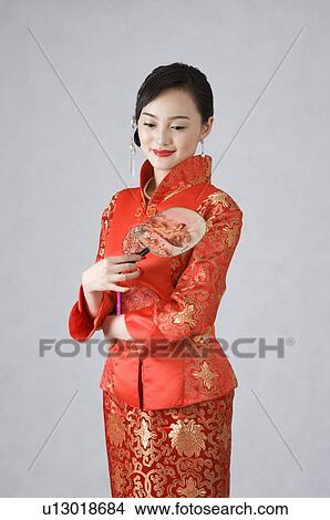 Young woman in cheongsam holding fan View Large Photo Image Picture - Young woman in cheongsam holding fan. Fotosearch