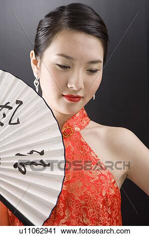 Young woman in cheongsam holding fan View Large Photo Image Stock Image - Young woman in cheongsam holding fan. Fotosearch