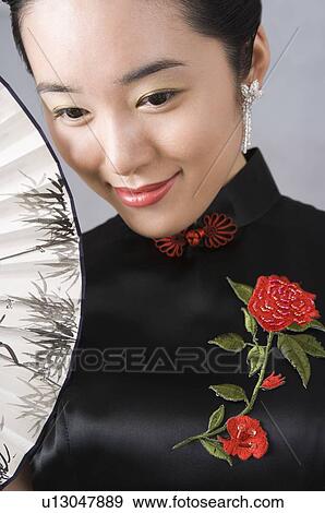 Young woman in cheongsam holding folding fan View Large Photo Image Stock Photo - Young woman in cheongsam holding folding fan. Fotosearch