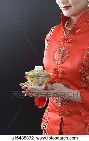 Young woman wearing a red traditional Chinese qipao, holding a traditional tea cup with both hands View Large Photo Image Stock Image - Young woman wearing a red traditional Chinese qipao, holding a traditional tea cup with both hands. Fotosearch