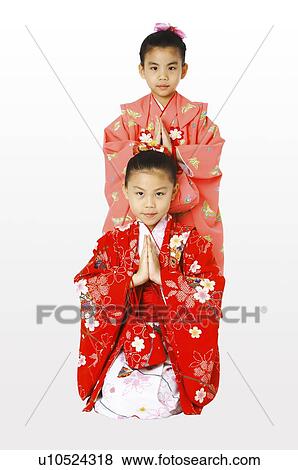 Stock Photo - A girl in kimono standing behind the kneeling girl. Fotosearch