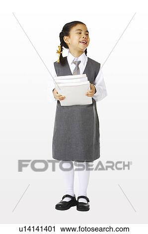 Stock Image - Girl in school uniforms holding three books. Fotosearch