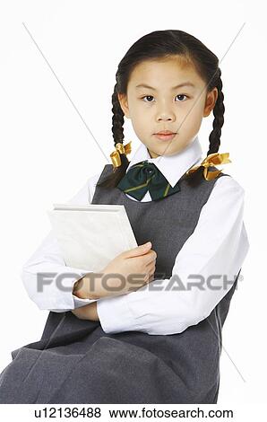 Stock Photo - Girl sitting on the stool holding a book. Fotosearch