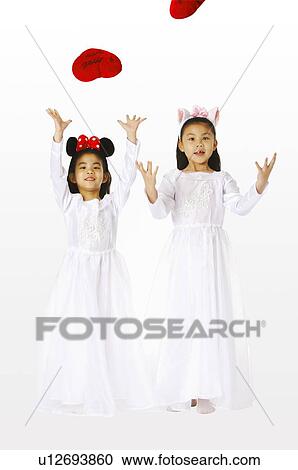 Two young girls wearing white dresses and headbands, playing with heart shaped toys View Large Photo Image Stock Image - Two young girls wearing white dresses and headbands, playing with heart shaped toys. Fotosearch