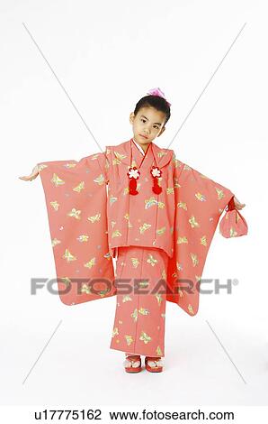 Stock Image - Young girl wearing a pink Japanese kimono, arms outstretched. Fotosearch