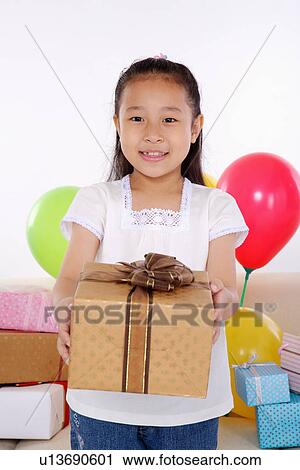 Girl holding wrapped gift, smiling, portrait View Large Photo Image Stock Image - Girl holding wrapped gift, smiling, portrait. Fotosearch