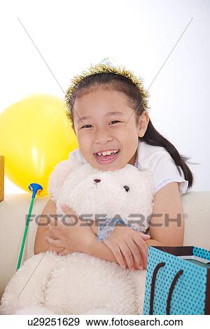 Girl leaning on sofa holding teddy bear View Large Photo Image Stock Photo - Girl leaning on sofa holding teddy bear. Fotosearch