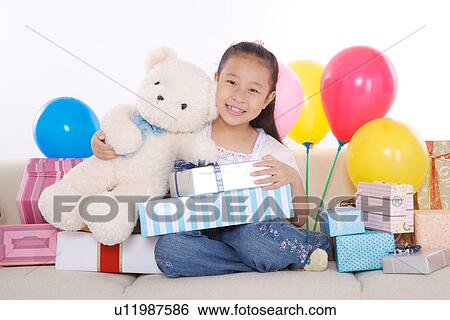 Stock Photograph - GIrl sitting on sofa with many gifts. Fotosearch