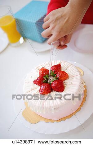 Stock Image - Hands cutting birthday cake together. Fotosearch