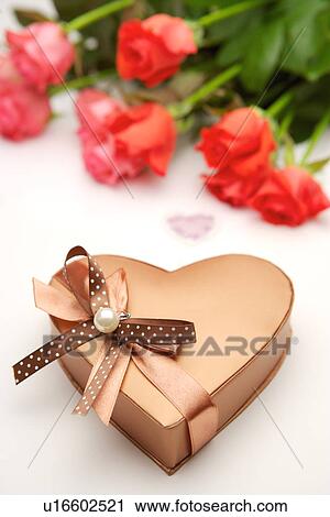 Stock Image - Heart shape wrapped gift and roses. Fotosearch