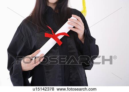 Stock Photo - One single woman wearing graduation gown holding certificate, mid section. Fotosearch