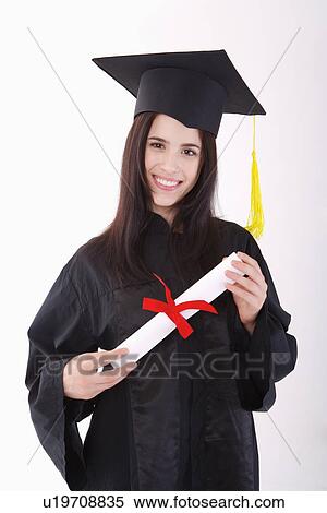 One young woman wearing graduation gown holding certificate, smiling, portrait View Large Photo Image Stock Photography - One young woman wearing graduation gown holding certificate, smiling, portrait. Fotosearch