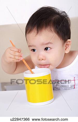 Stock Photograph - Baby boy eating food, portrait. Fotosearch