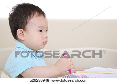 Stock Photo - Baby boy holding felt tip pen looking away. Fotosearch