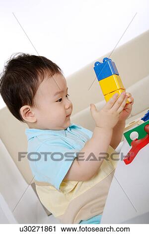 Stock Image - Baby boy playing block, side view, portrait. Fotosearch