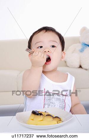 Baby girl putting spoon in mouth, portrait, close-up View Large Photo Image Stock Photo - Baby girl putting spoon in mouth, portrait, close-up. Fotosearch