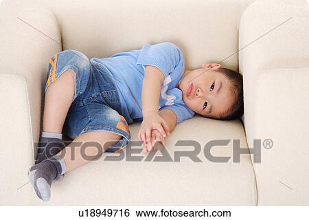 Boy lying on sofa View Large Photo Image Stock Photograph - Boy lying on sofa. Fotosearch