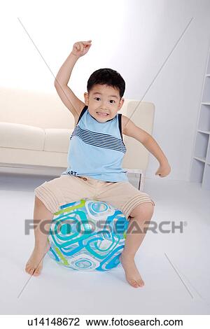 Boy sitting on ball indoors View Large Photo Image Stock Image - Boy sitting on ball indoors. Fotosearch