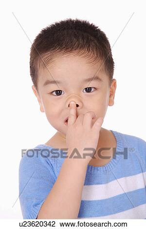 Stock Image - Boy touching his nose, close up, portrait. Fotosearch