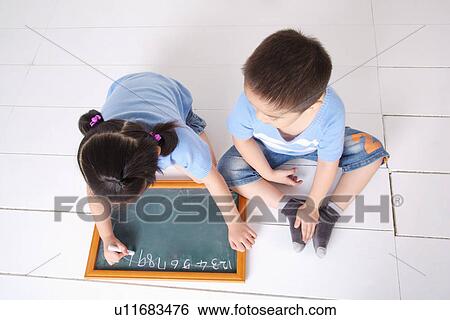 Stock Photograph - Children sitting on floor with chalkboard. Fotosearch