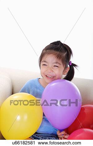 Girl sitting on sofa surrounded by balloons View Large Photo Image Stock Image - Girl sitting on sofa surrounded by balloons. Fotosearch