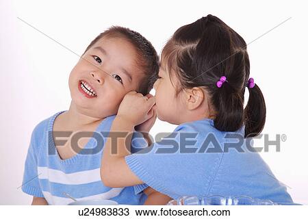 Girl whispering into boy's ear View Large Photo Image Stock Image - Girl whispering into boy's ear. Fotosearch