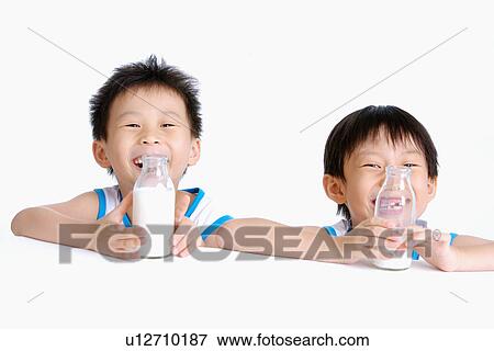Two boys holding milk bottle, smiling, portrait View Large Photo Image Stock Photo - Two boys holding milk bottle, smiling, portrait. Fotosearch