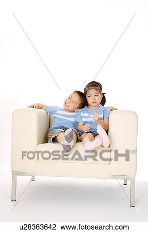 Two children sitting on sofa View Large Photo Image Stock Image - Two children sitting on sofa. Fotosearch