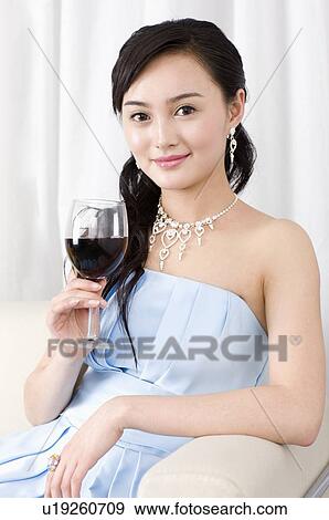 Smiling young woman in a blue evening dress, holding a glass of red wine, sitting View Large Photo Image Stock Photo - Smiling young woman in a blue evening dress, holding a glass of red wine, sitting. Fotosearch