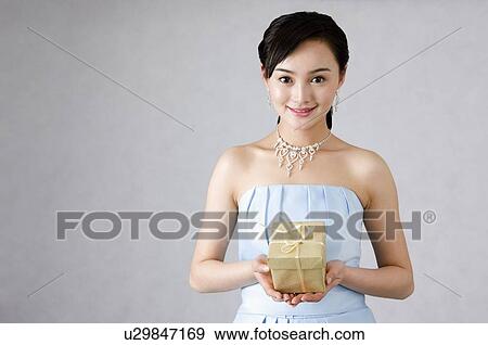 Smiling young woman in blue dress, holding a wrapped present View Large Photo Image Stock Photo - Smiling young woman in blue dress, holding a wrapped present. Fotosearch