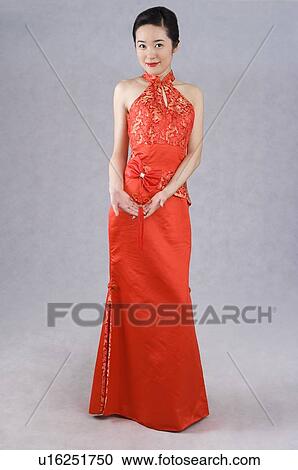Stock Image - Young Chinese woman wearing a red cheongsam, smiling. Fotosearch