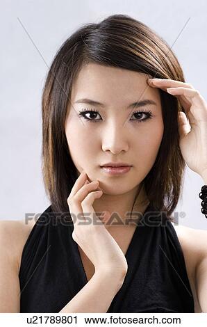 Stock Image - Young woman, hands touching face, close-up. Fotosearch