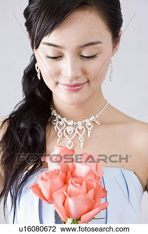 Young woman in a blue evening gown, holding pink roses, looking down View Large Photo Image Stock Image - Young woman in a blue evening gown, holding pink roses, looking down. Fotosearch