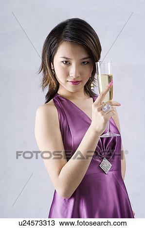 Young woman wearing a purple dress, holding a glass of champagne View Large Photo Image Stock Image - Young woman wearing a purple dress, holding a glass of champagne. Fotosearch