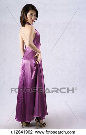 Young woman wearing a purple evening gown and high heels, rear view, head turned, hand on hip View Large Photo Image Stock Image - Young woman wearing a purple evening gown and high heels, rear view, head turned, hand on hip. Fotosearch