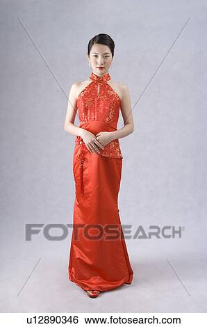 Stock Photograph - Young woman wearing a red cheongsam with embroidery, hands folded in front. Fotosearch