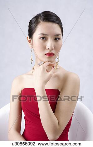 Young woman wearing a red dress and jewelry, dressed up, hand on chin View Large Photo Image Stock Image - Young woman wearing a red dress and jewelry, dressed up, hand on chin. Fotosearch
