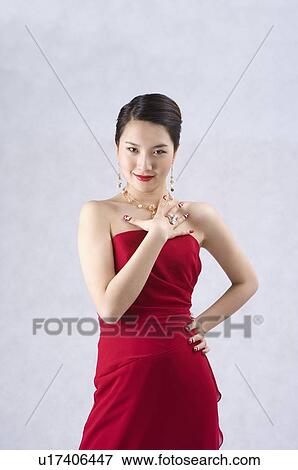 Stock Photo - Young woman wearing a red dress and jewelry, dressed up. Fotosearch