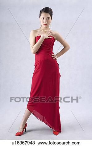Stock Photo - Young woman wearing a red evening gown and high heels, posing. Fotosearch