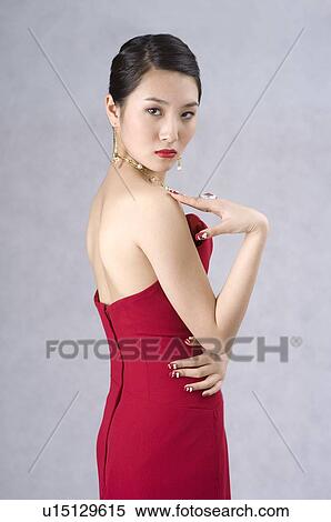 Young woman wearing a red evening gown, side view, head turned to front View Large Photo Image Stock Photography - Young woman wearing a red evening gown, side view, head turned to front. Fotosearch