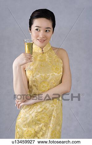 Young woman wearing a yellow embroidered cheongsam, holding a glass of champagne View Large Photo Image Stock Photo - Young woman wearing a yellow embroidered cheongsam, holding a glass of champagne. Fotosearch
