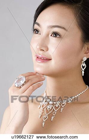 Young woman wearing jewelry, hand on chin View Large Photo Image Stock Photo - Young woman wearing jewelry, hand on chin. Fotosearch