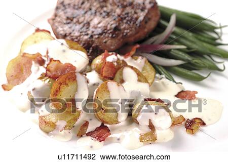 Stock Image - Saucy potatoes, steak and french beans. Fotosearch