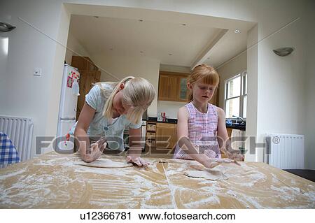 Stock Image - Young girls making pastry. Fotosearch