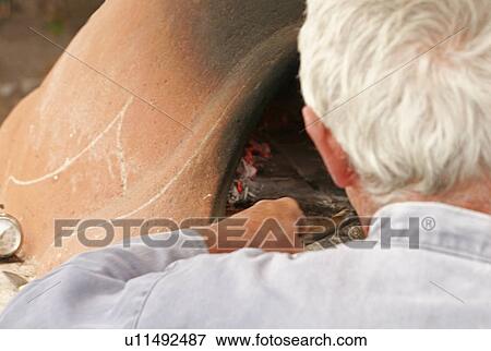 Clay oven, man moving embers View Large Photo Image Stock Photo - Clay oven, man moving embers. Fotosearch