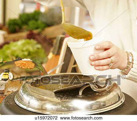 Stock Image - Serving carrot and coriander soup on a market. Fotosearch