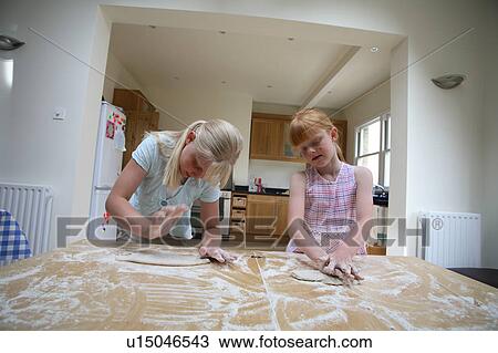 Stock Image - Young girls making pastry. Fotosearch